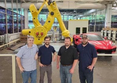 Invent Automation team standing in front of a yellow robotic machine